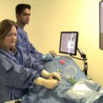 Iris Grunwald (left) demonstrates the use of a surgical simulator thumbnail